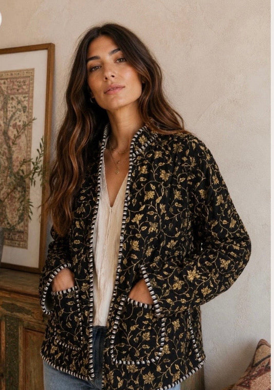 model wearing black corduroy jacket with gold floral pattern.  models hands are in the jacket pockets