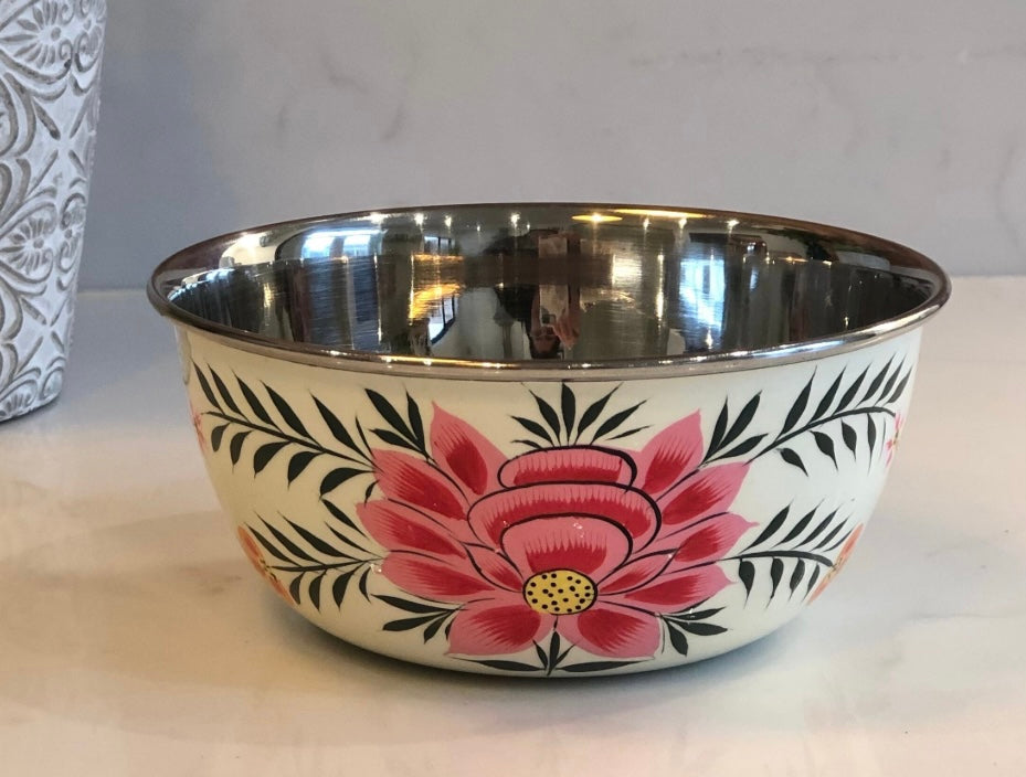 Metal mixing bowl with floral design on a white surface