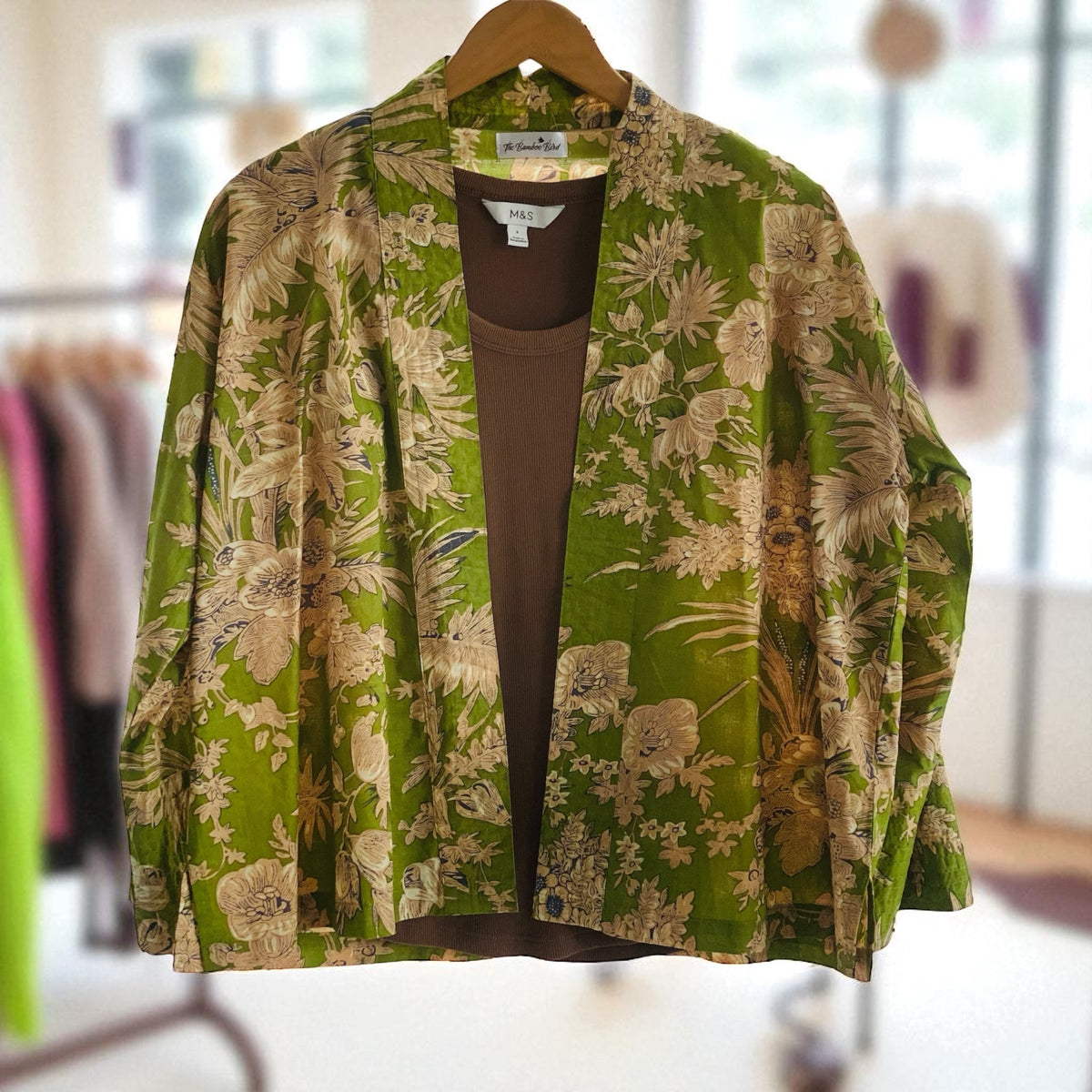 Olive green kimono jacket with cream flowers on a hangar