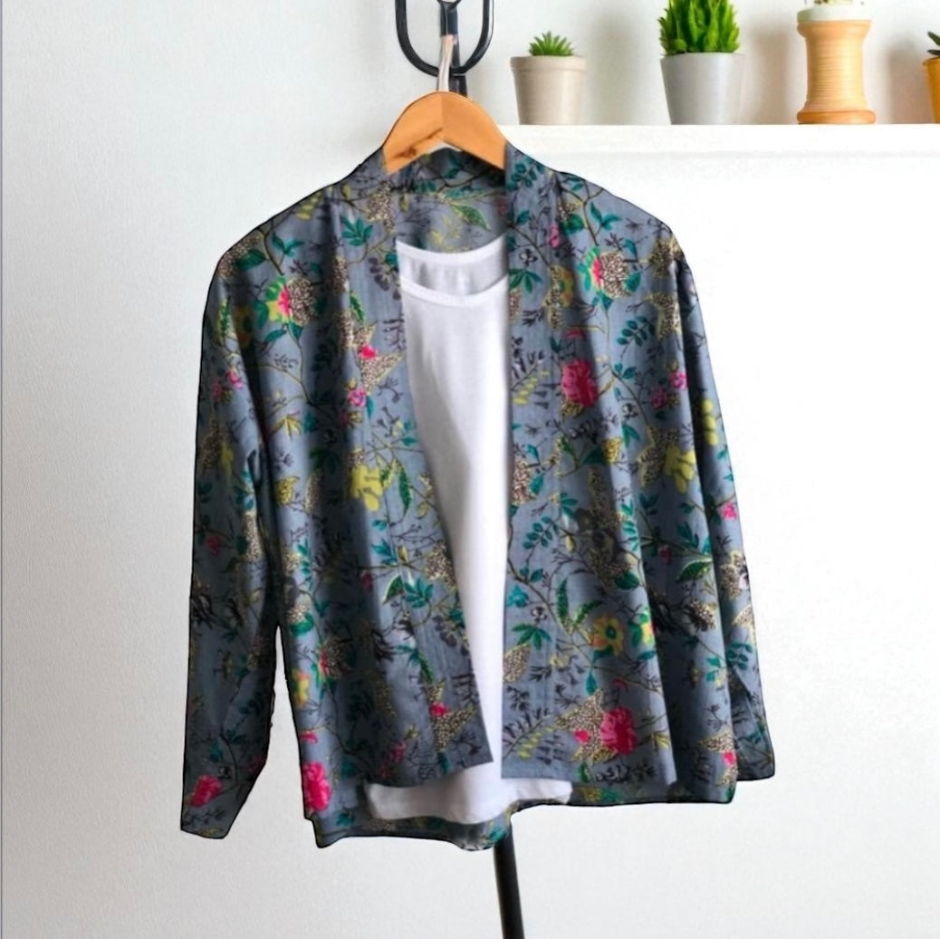 Floral patterned kimono jacket on a hanger against a white wall with plants in the background