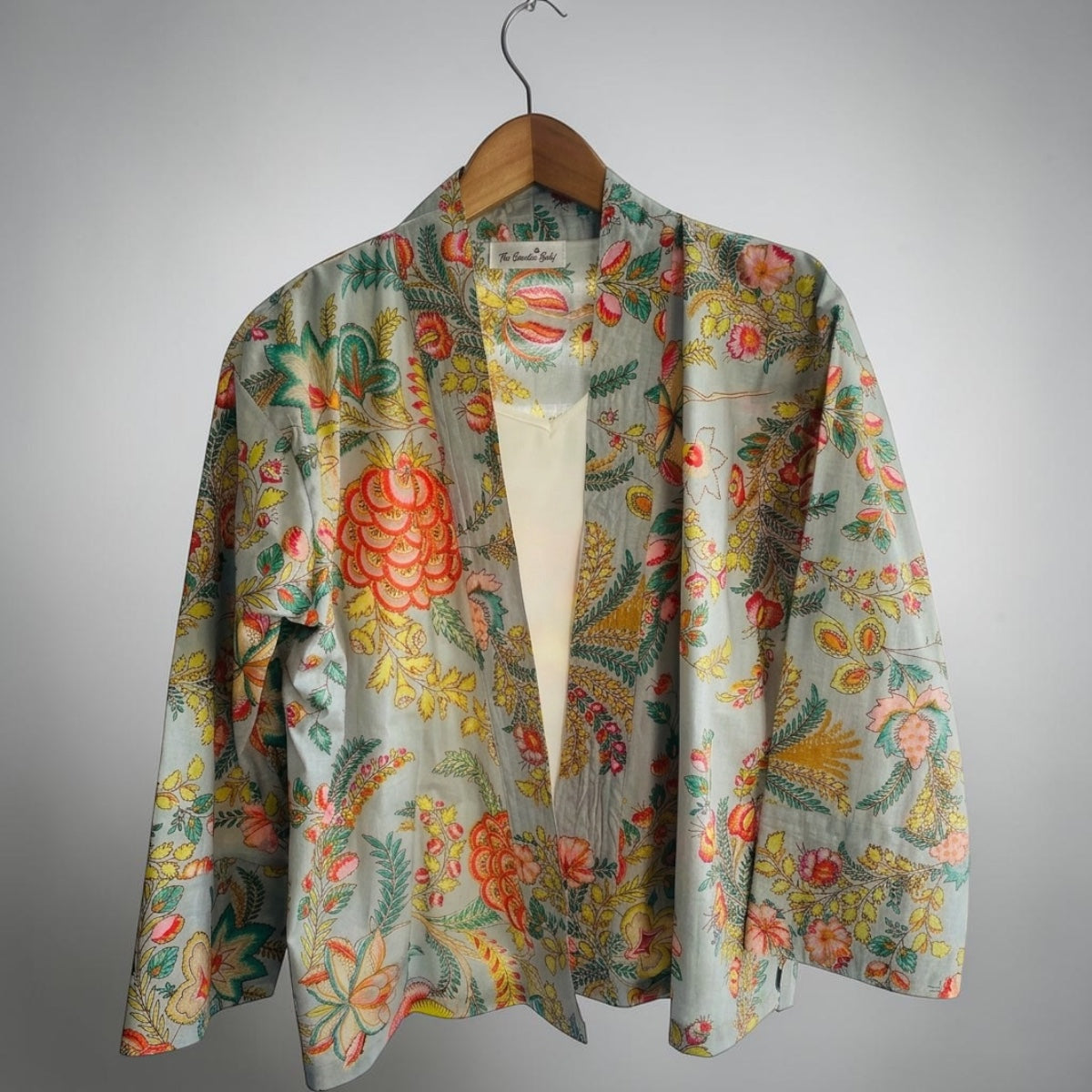 pale blue kimono jacket with pink and yellow flowers on wooden hangar