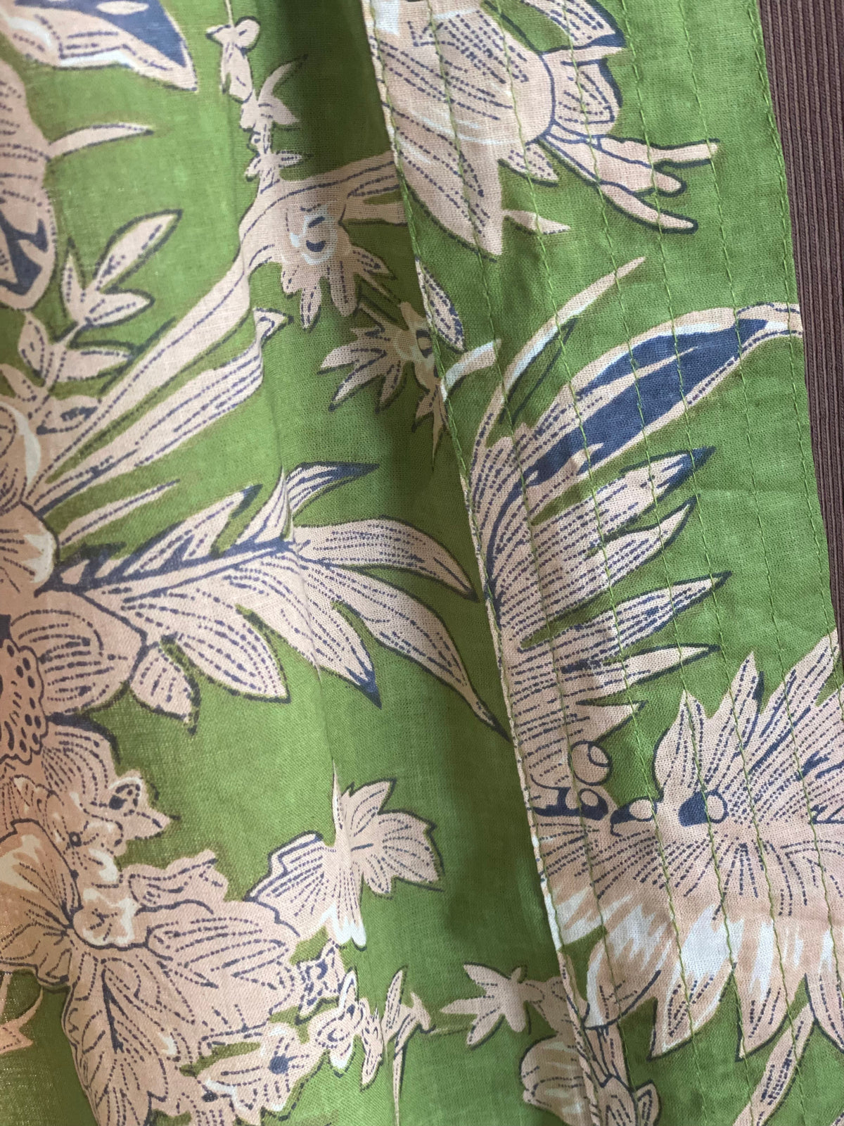 Close up of olive green fabric with cream and blue flowers