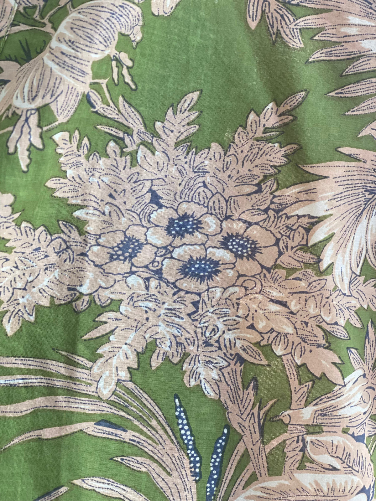 Close up of olive green fabric with cream flowers and blue highlights
