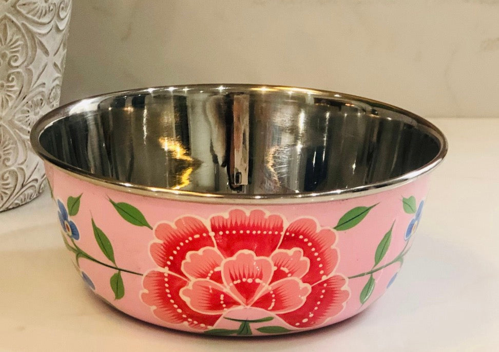 A pink enamel pet bowl with a large red and pink floral design and green leaves, featuring a polished stainless steel interior.
