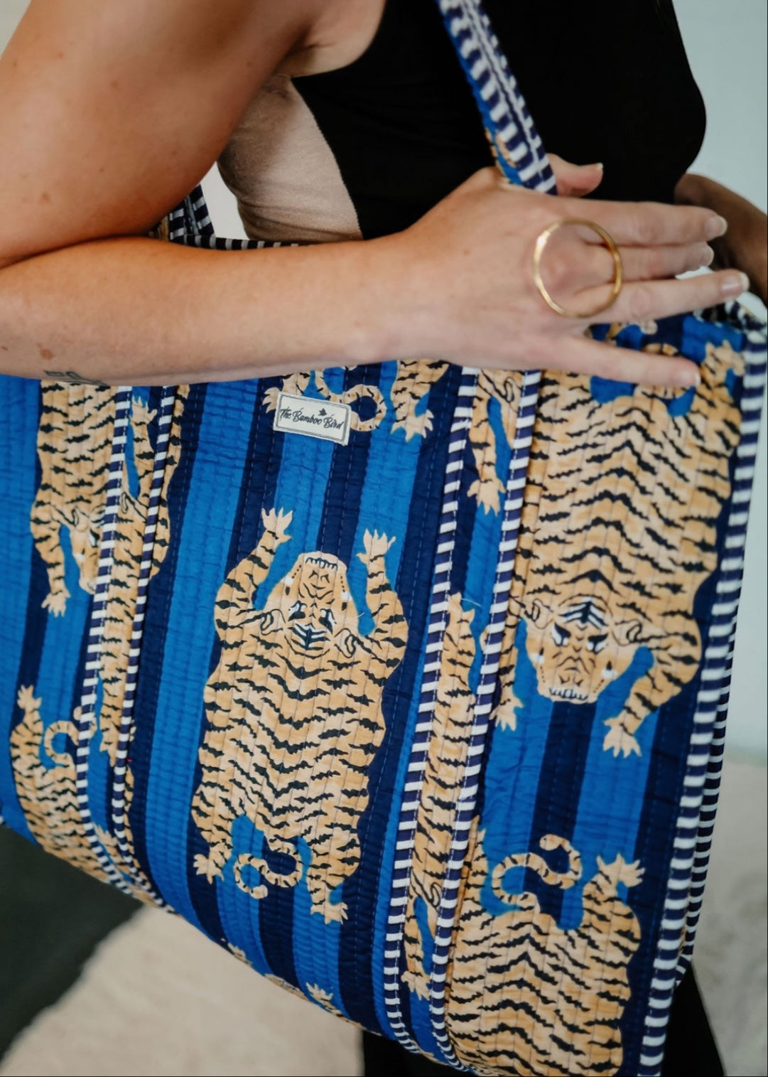 The Bamboo Bird blue quilted cotton tote bag featuring a hand block-printed tiger pattern and striped shoulder straps.