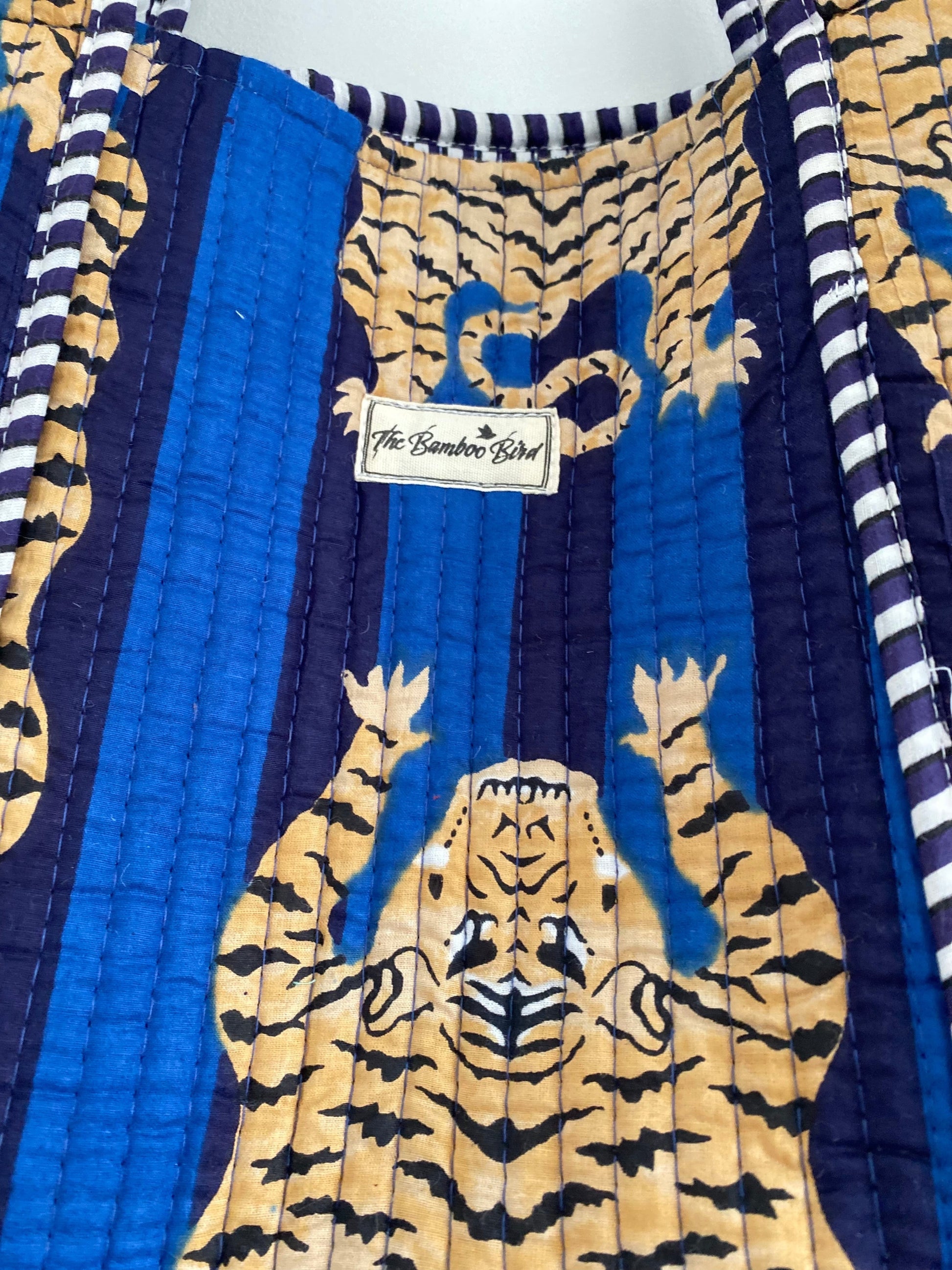 The Bamboo Bird quilted cotton tote bag featuring a blue and yellow hand block-printed tiger pattern and striped trim.