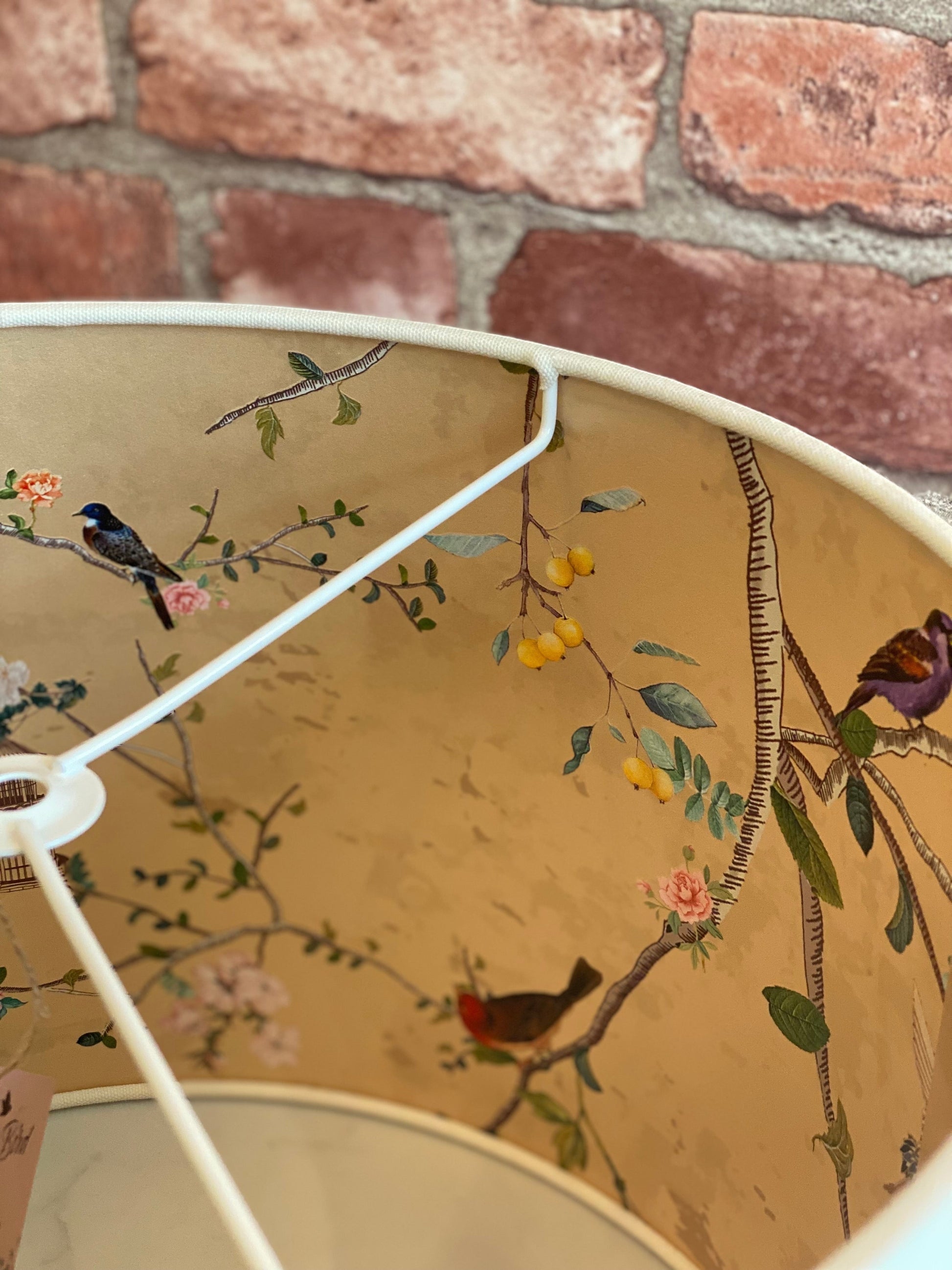 The Bamboo Bird handmade drum lampshade with a cream exterior and an intricate gold chinoiserie bird and floral lining.