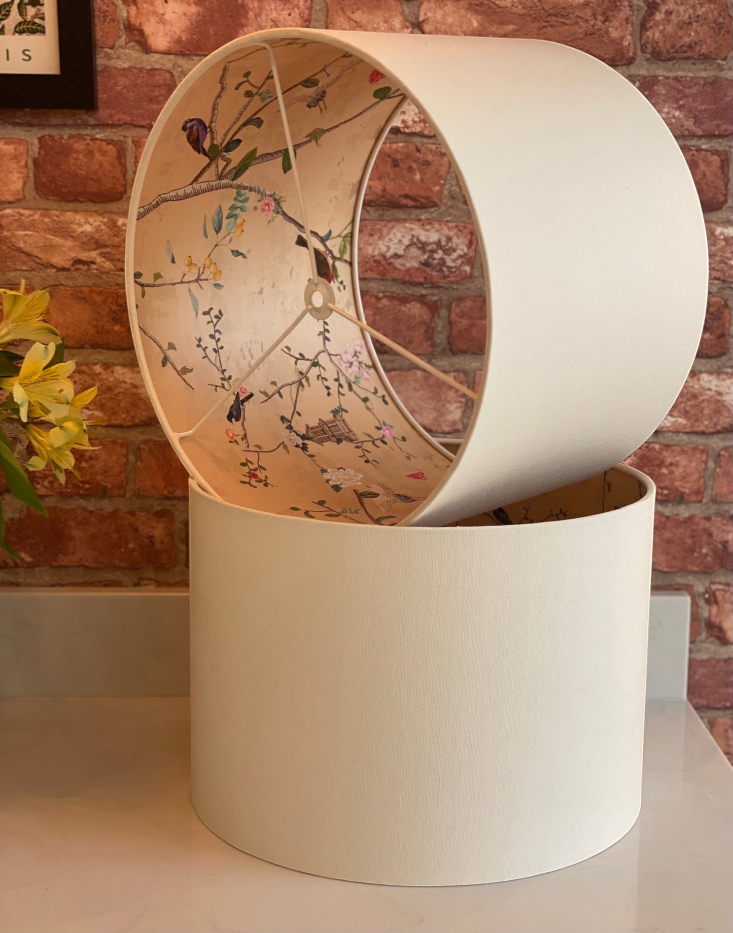 The Bamboo Bird cream linen drum lampshade featuring an interior lining with a chinoiserie bird and botanical pattern.
