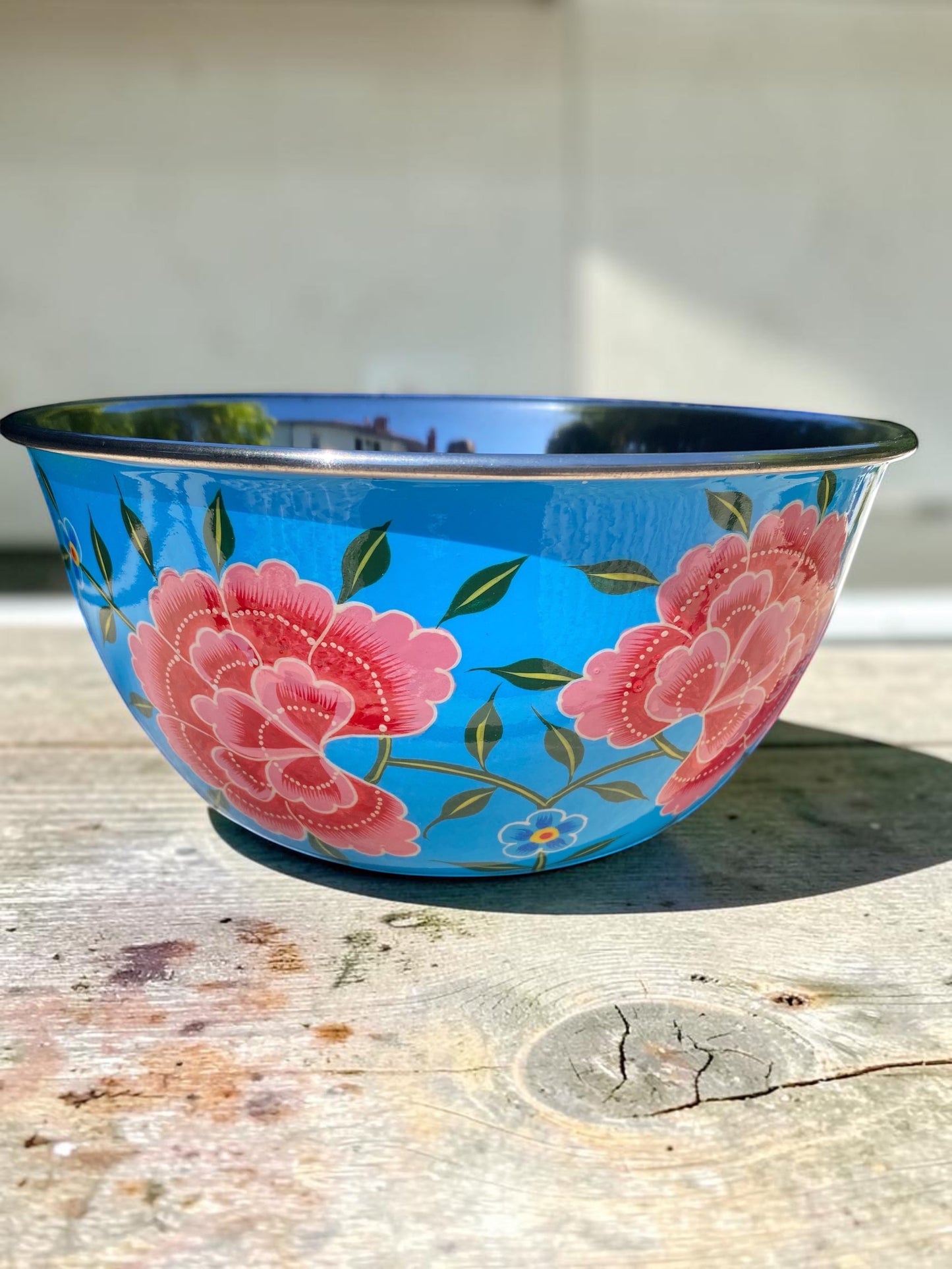 The Bamboo Bird hand-painted stainless steel and enamel bowl in bright blue with pink floral patterns.