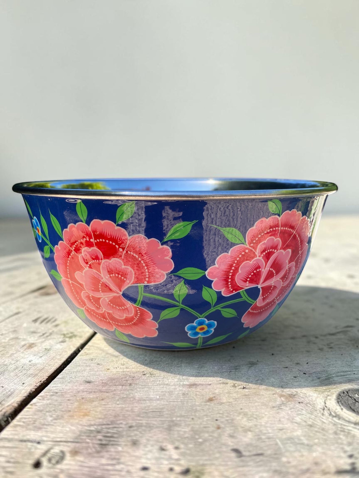 The Bamboo Bird hand-painted stainless steel and enamel bowl featuring vibrant pink floral patterns on a blue base.