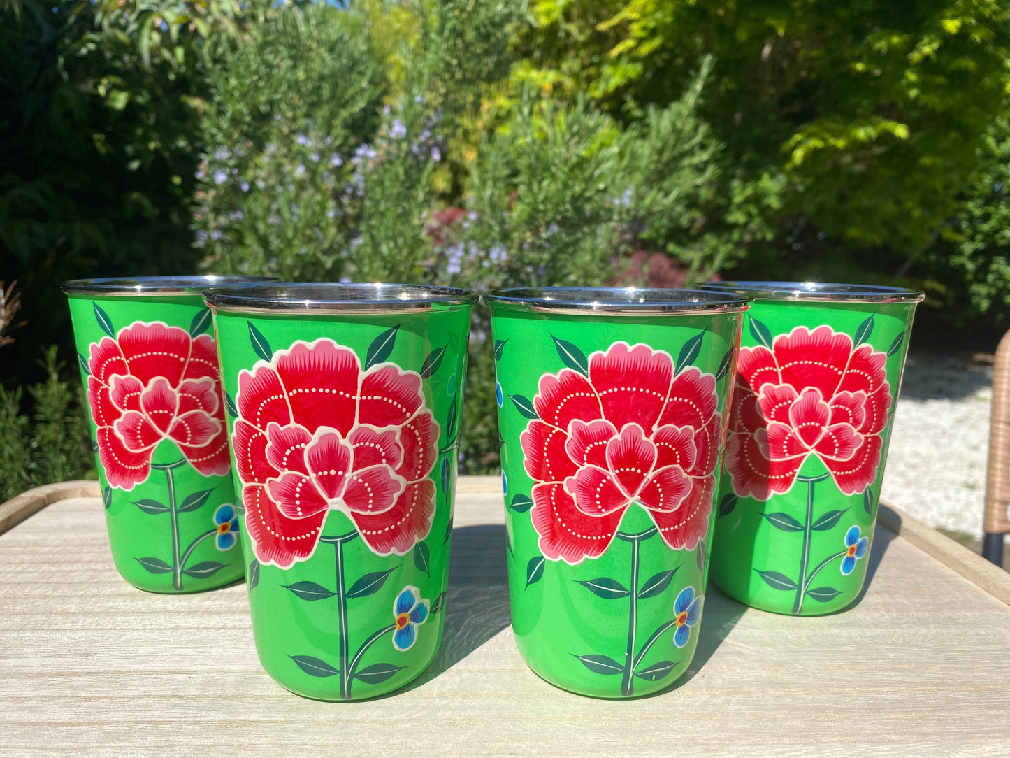 The Bamboo Bird set of four green stainless steel tumblers with hand-painted red floral designs from Kashmir.