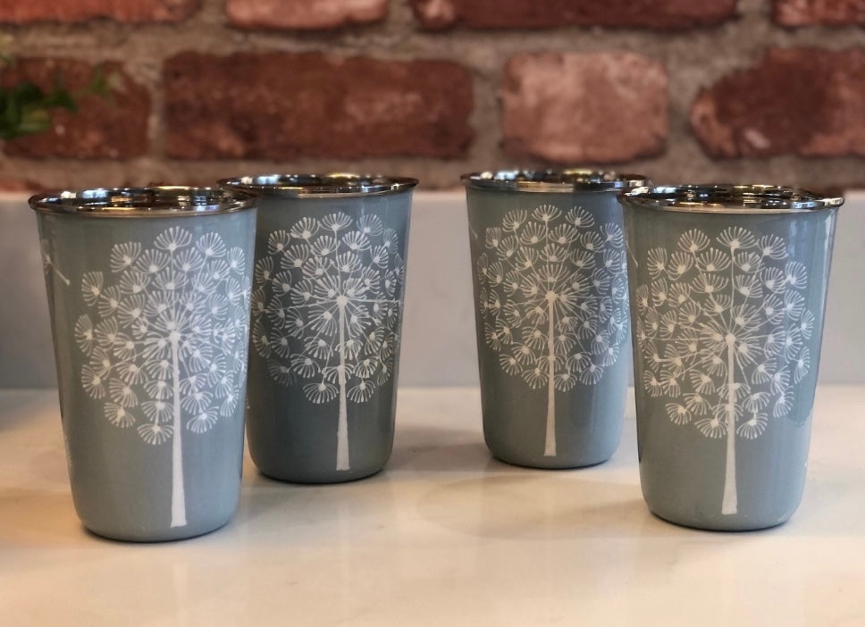 The Bamboo Bird set of four grey stainless steel tumblers featuring hand-painted white dandelion floral designs.