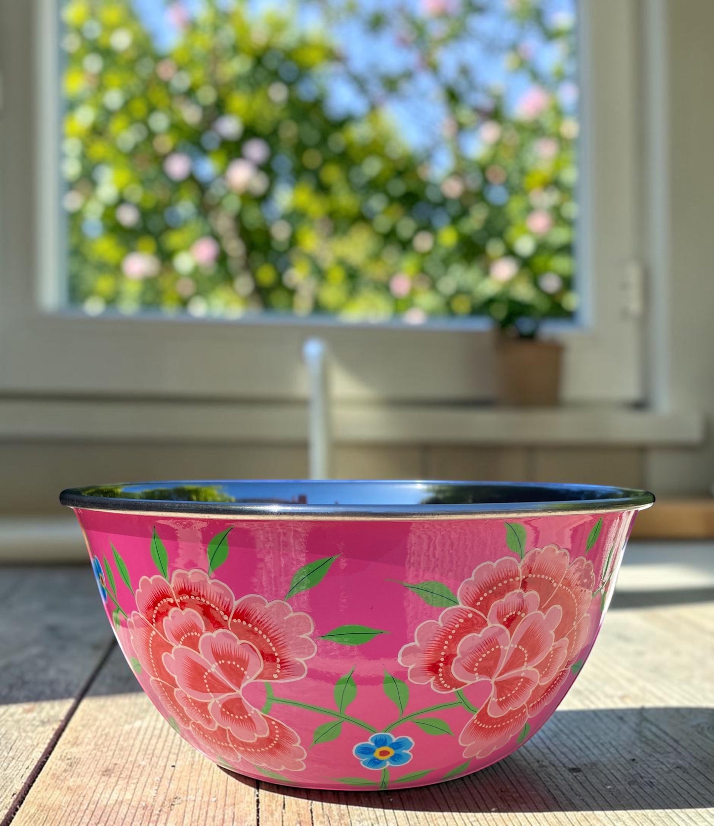 The Bamboo Bird hand-painted pink stainless steel and enamel bowl with floral design on a wooden surface