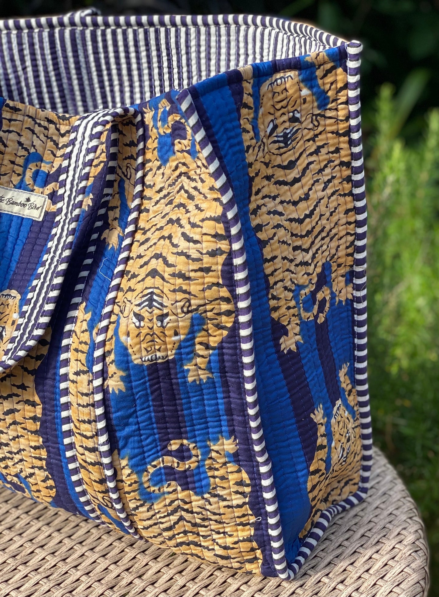 The Bamboo Bird quilted cotton tote bag featuring a blue and gold tiger print with striped trim and sturdy straps.